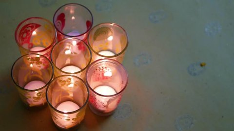Hindu festival of lights, Dusshera and Diwali preparation and celebration ingredients- decorative painted glasses with t-candles and flowers being added by a human hand : stockvideo