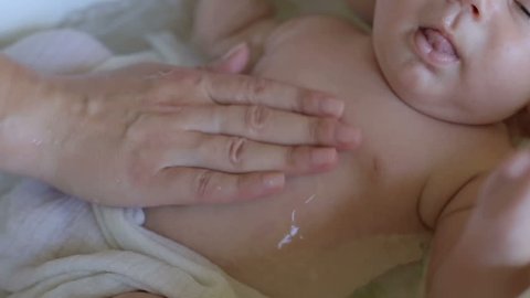 Mother is bathing infant at the hands
