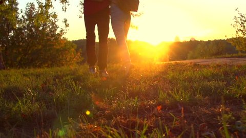 Happy joyful young couple walking in a park together, holding hands. Love, dating concept. Boyfriend takes hand of his girlfriend outdoors. Slow motion 240 fps, high speed camera. Full HD 1080p