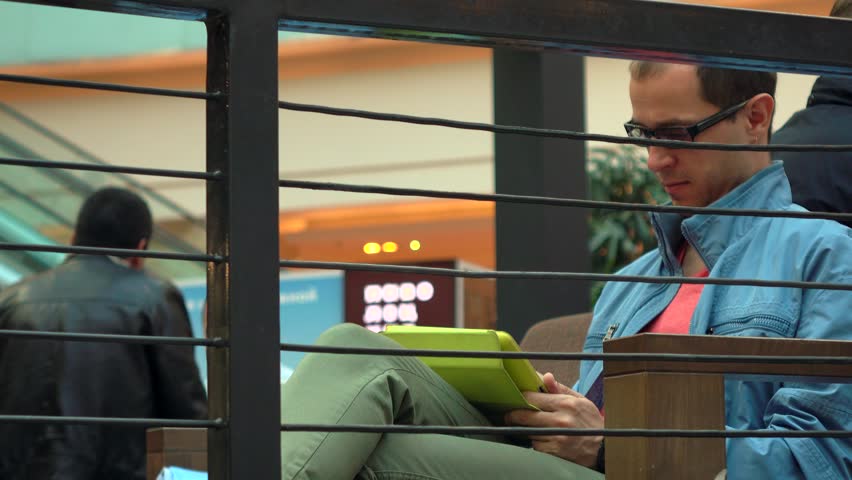 Serious man in black rim glasses using his tablet computer in cafe. 4K shot