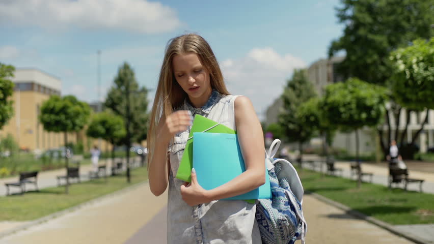 Worried student standing on pathway and having a headache
