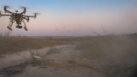 Custom drone hexacopter takes off from the field. Slow motion.