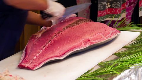 Chef cook hands cutting with knife big bluefin tuna fish HD video in sushi restaurant. Asian Japanese cuisine.