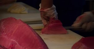 Chefs hands cutting and scrape tuna fish filet 4k close up video in sushi restaurant kitchen. Asian japanese cuisine.