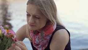Very smudge girl looking sad while sitting next to the water and holding flowers
 - Powered by Shutterstock - Get 15% off with code: PIKWIZARD15