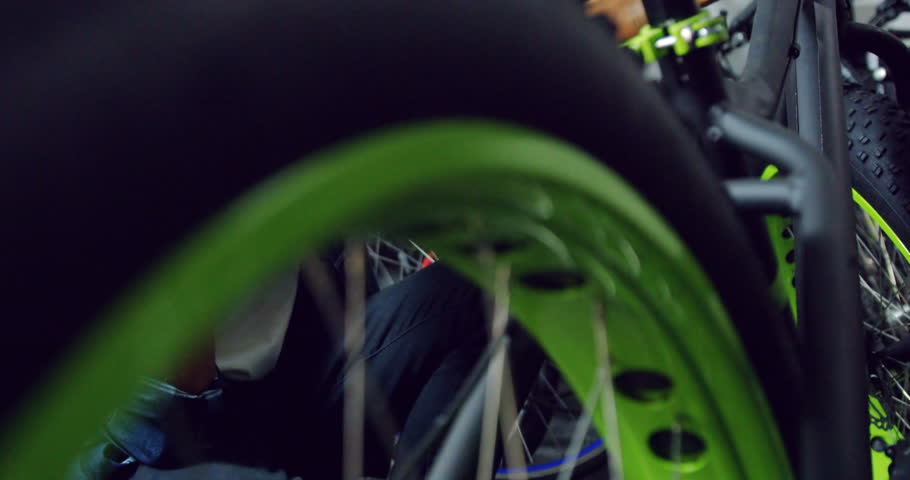 Mechanic talking on mobile phone while repairing bicycle in workshop