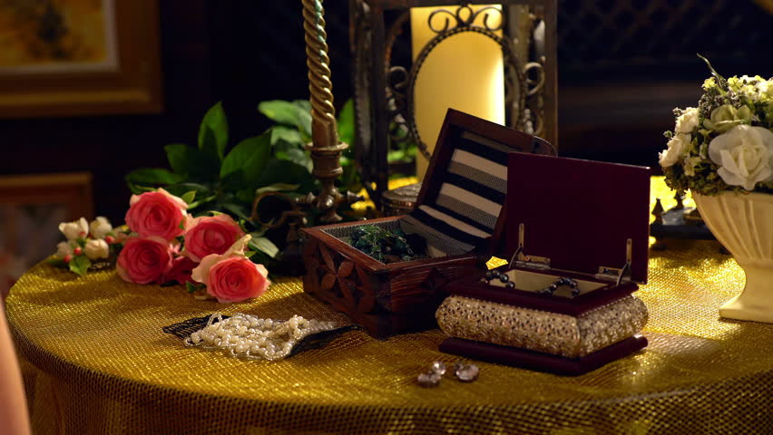Girl behind dressing table puts on jewelry. Dressing table with boxes and women