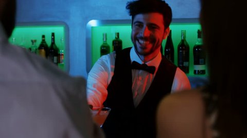 Bartender serving drinks to customers at bar counter 4K