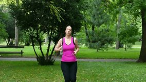 A young woman runs and drinks water in a beautiful green park in slow motion, The Slow Motion of Running In a Nature, Slow Motion Video Clip