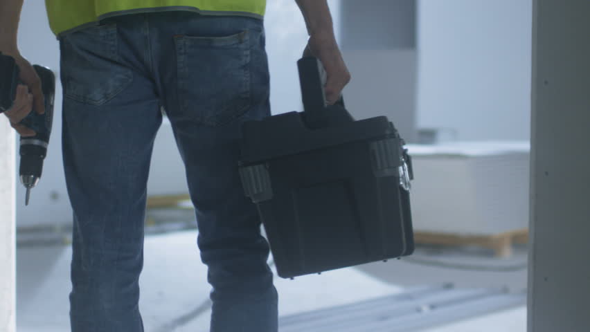 Construction Worker Walking inside Building Under Construction and Carrying Toolbox. Shot on RED Cinema Camera in 4K (UHD). Royalty-Free Stock Footage #19626892