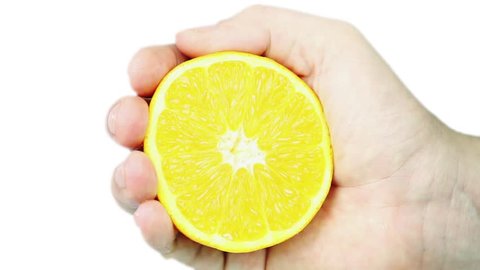 a male hand squeezes an orange, juice runs and drops out