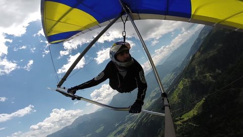 Man performs maneuvers on a hang-glider. He rotates in a spiral and handles a thermal, gaining altitude. Shooting with on-board GoPro camera