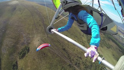 Woman on a hang glider flying over the paraglider. View from the hangglider. Shooting with on-board GoPro camera.