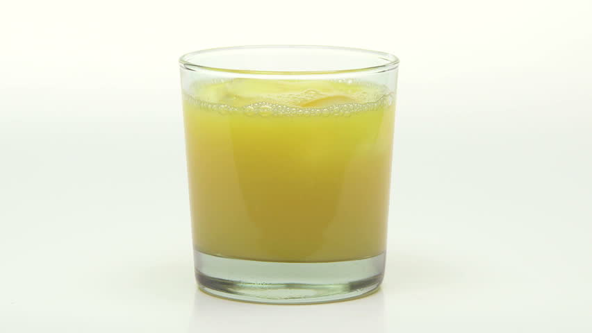 Orange Juice being poured into a glass with ice cubes
