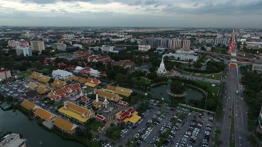 aerial bird eye view moving forward over the temple in Bangkok Thailand with traffic in the evening sky