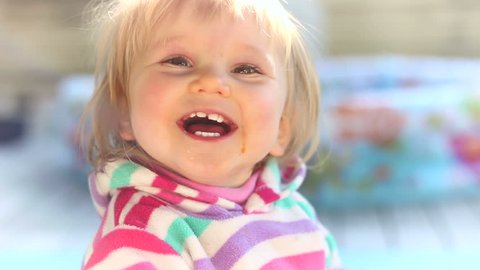 Cute baby girl playing outside and smiling at the camera.
