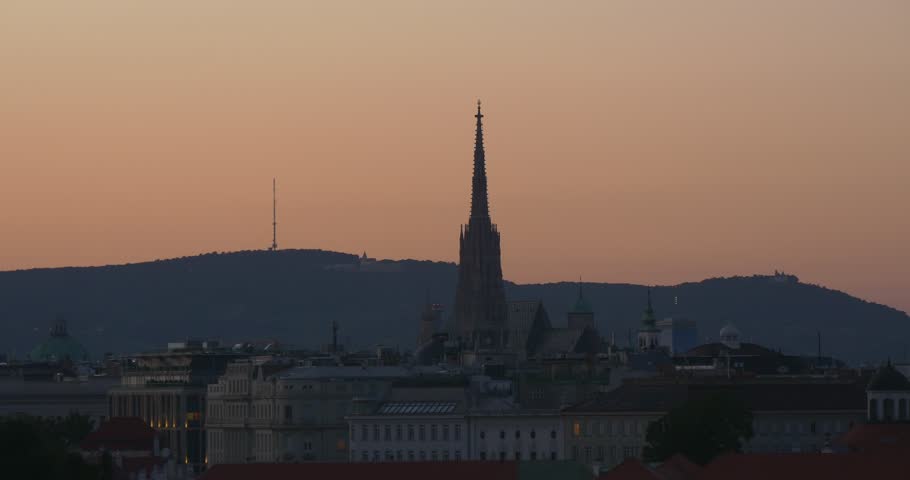 Panoramic view of city in sunset. Big tower of gothic cathedral on beige clear sky