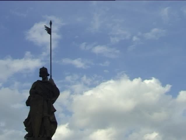 Clouds are rolling behind silhouette statue.