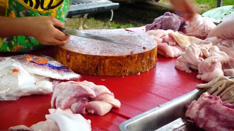 Close up of a woman cutting the skin off a pig in local market, Thailand 