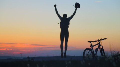 Jump on heart mountain. Silhouette happy cyclist, overcame many obstacles to reach the top.
