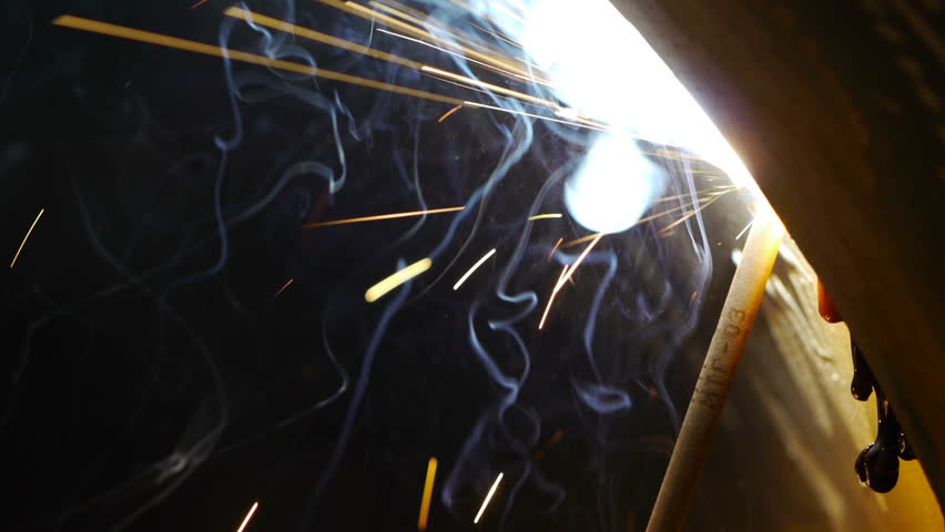 welding metal pipe, closeup sparks and flash