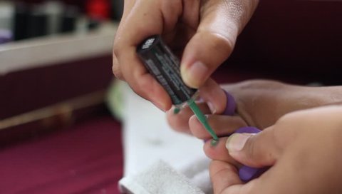 Close-up of pedicurist applying nail polish to the toenails, selective focus