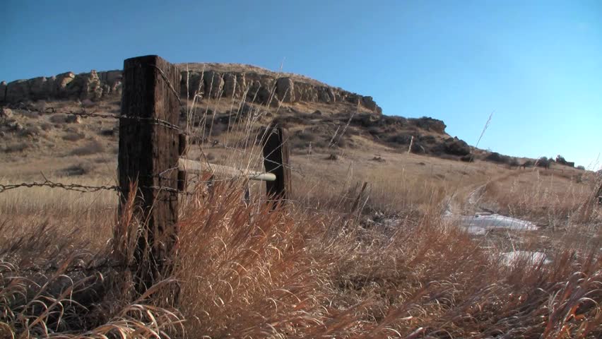 Western fence in front of rock bluff.