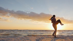 A young man in love at the hands circling his bride. On the beach at sunset. Slow motion video