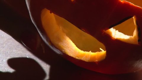 Insert vampire fangs in Halloween pumpkin mouth, closeup shot