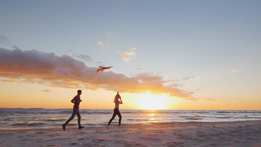 Young couple playing with a kite on the beach at sunset. Steradicam slow motion shot | Shutterstock HD Video #19687261