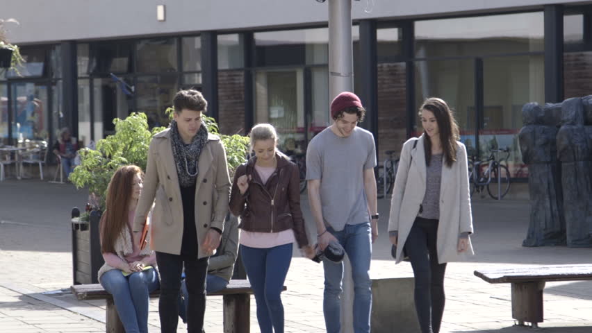 Two young couples walking through the city. They are wearing casual clothing and smiling. 