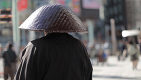 Shallow depth of field video of unidentified elderly monk from behind with blurred out pedestrians in Tokyo, Japan