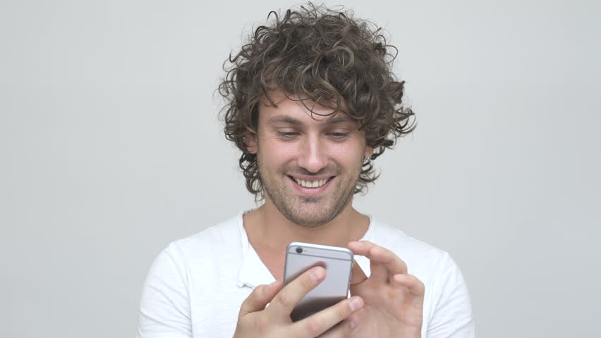 Smiling curly man using smartphone 