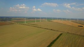 4K HD Wind turbine farm aerial video fly over ecological technologies power generating windmills produce clean renewable energy in countryside fields local road cars moving in distance Europe, Germany