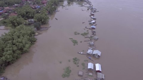 Aerial drone shot: Silder shot right-to-left over the Asian village flooded by the swollen the Mekong river