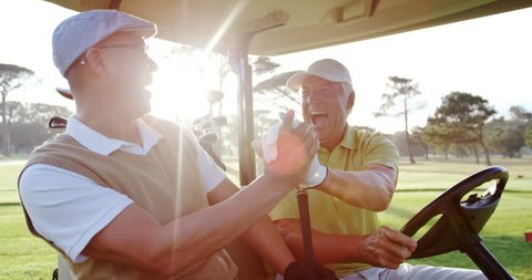 Two golfers laughing together in their golf buggy at golf course