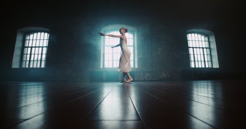 beautiful ballerina in white dress performs pirouettes in the Studio, slow motion