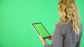 Backview of businesswoman on green background with digital tablet