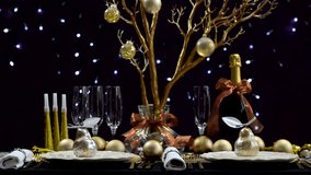 New Years Eve party dinner table with gold, white and black theme with flickering Christmas fairy lights, full table, front focus, static.  
