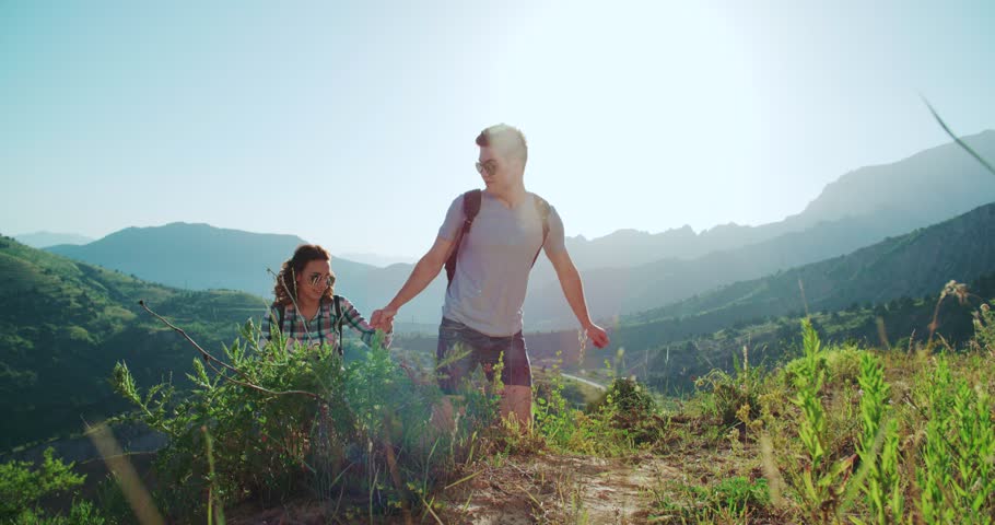 Couple climbing mountain range, hand reaches out to help,slow motion