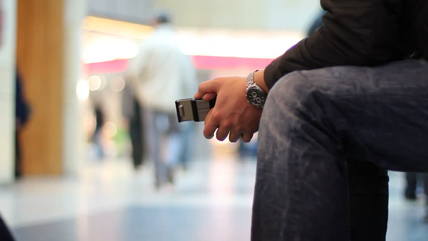 Man with cellphone waits at the shopping mall