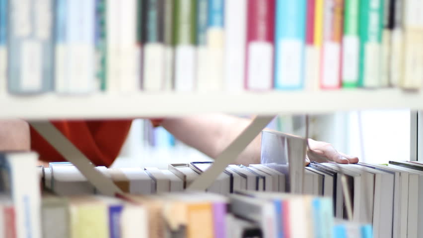 Student looks for textbook on library shelf
