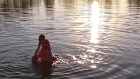 Boy dropping girl from his shoulders in water of lake, mobile phone video.