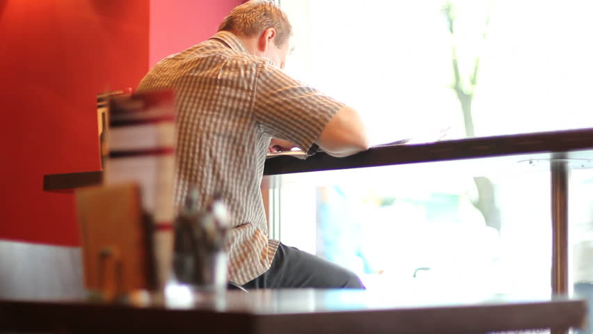 Man reading newspaper in cafe