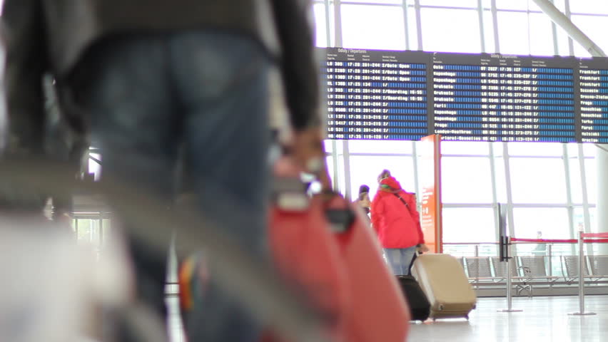 People with luggage and departures timetable at the airport