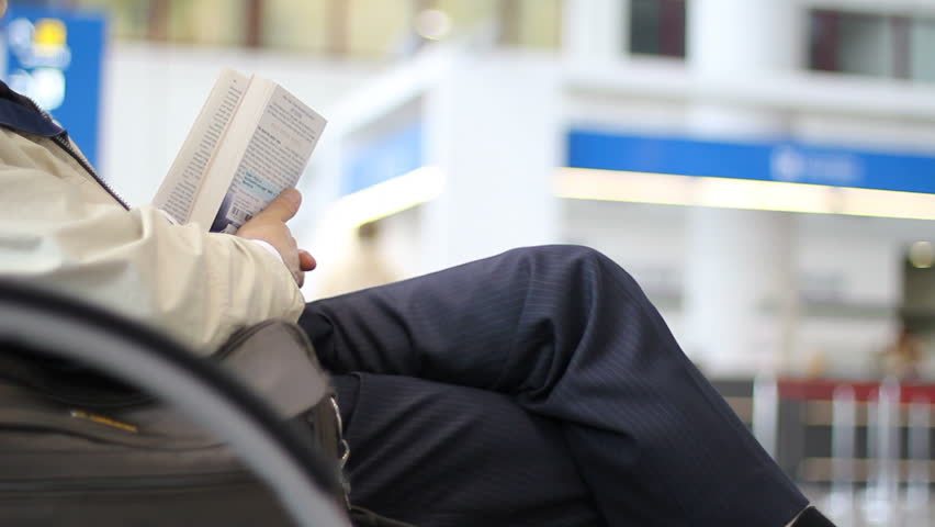 Man with book waits at the airport