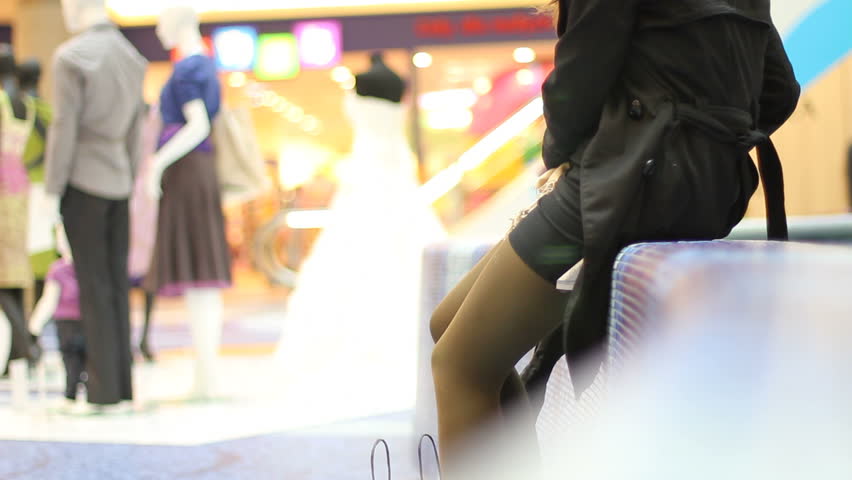 Elegant woman rests on bench in shopping mall