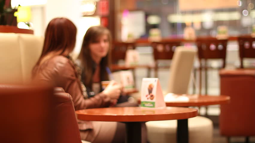 Two female friends enjoy coffee in cafe
