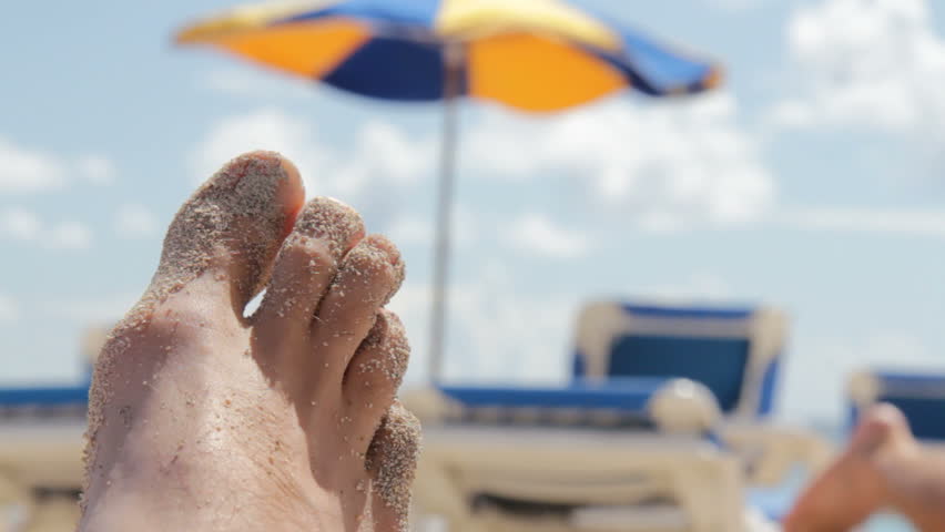 Male toes covered in sand on the beach