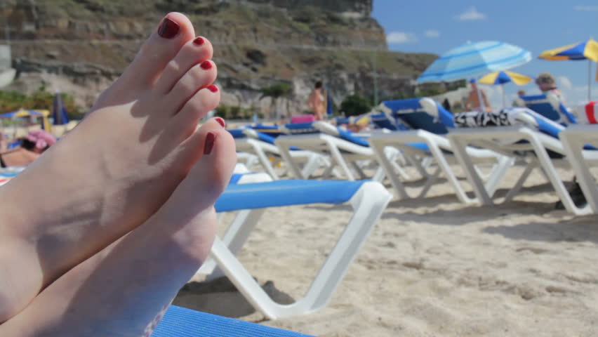 Female feet on a deckchair on the beach